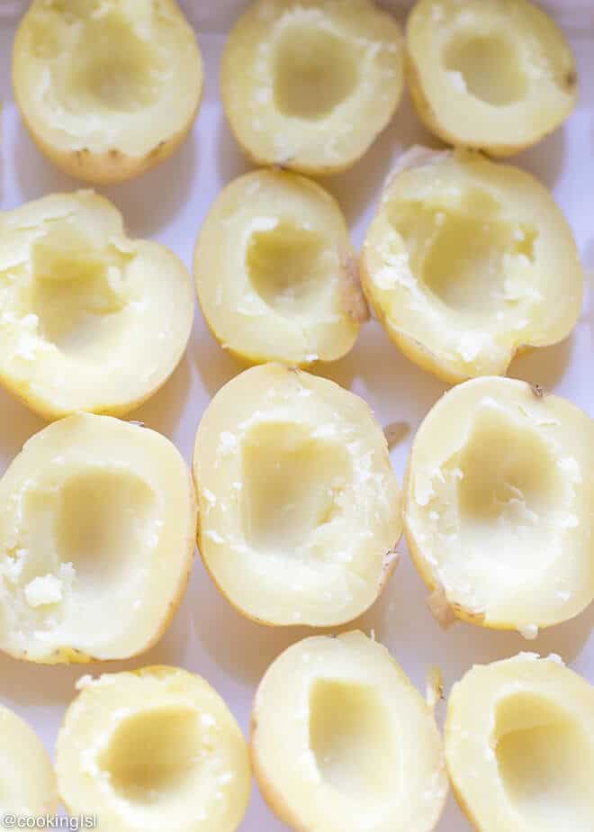 Cheesy Crispy Baked Potato Bites Recipe - boiled potatoes on a epicurean baking dish, with the inside scooped out.