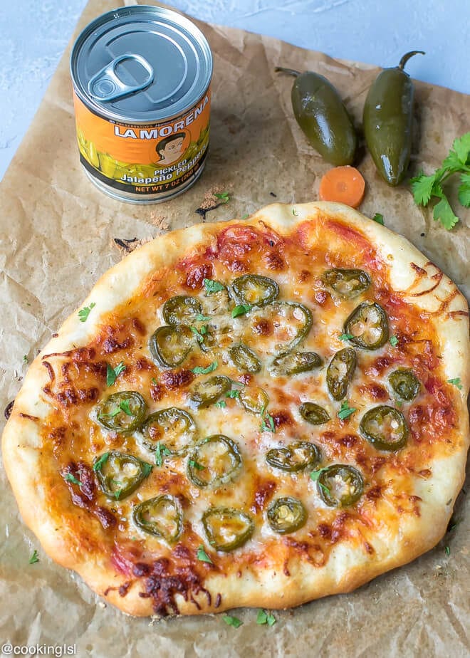 A whole cheese pizza topped and baked with LA MORENA® Pickled Jalapeño peppers.Canned Jalapeno Pizza Recipe . On a parchment paper with peppers on the side. 
