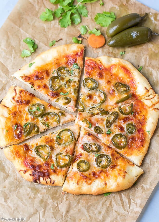 Canned Jalapeno Pizza Recipe. Pizza on a brown parchment paper, wsliced, topped with cilantro and jalapeño peppers on the side.