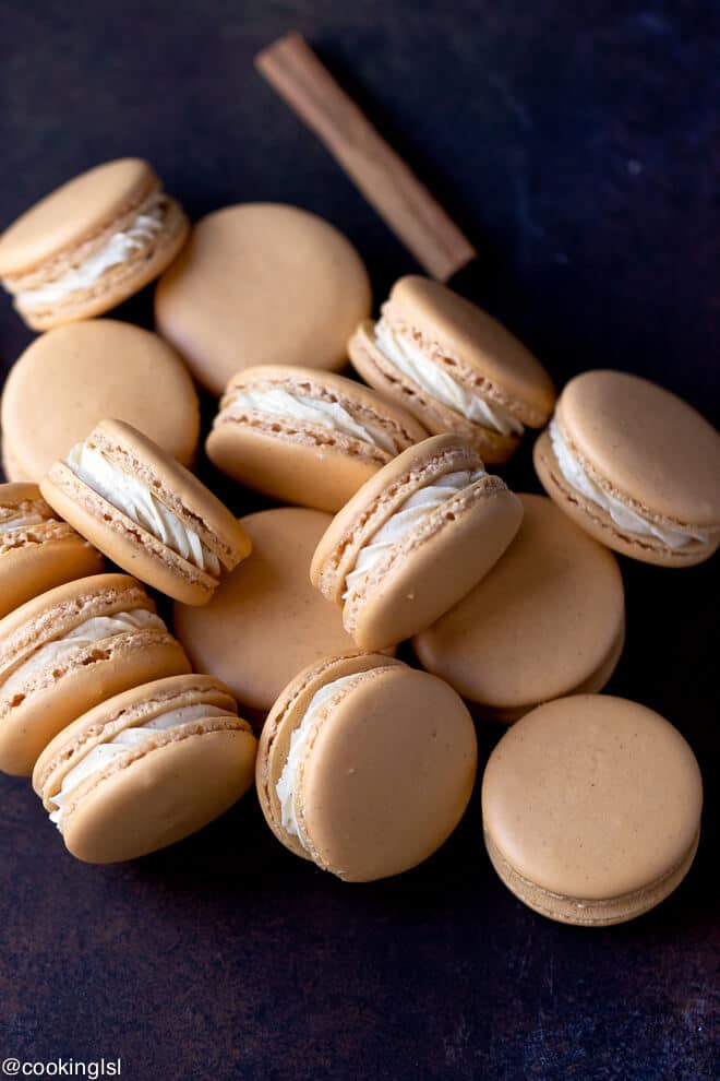 Pumpkin Spice Macarons Recipe -light orange macarons, with fal flavors stacked on a wooden board.