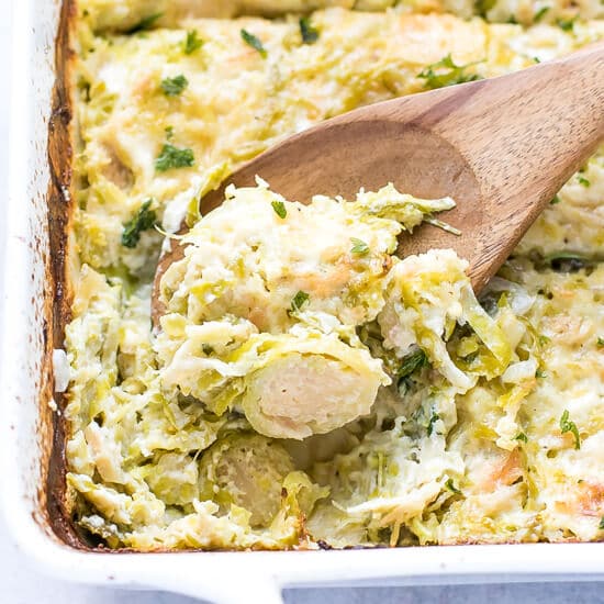 A white porcelain dish with tender, creamy Shaved Brussel Sprouts Gratin With Gruyere Recipe.