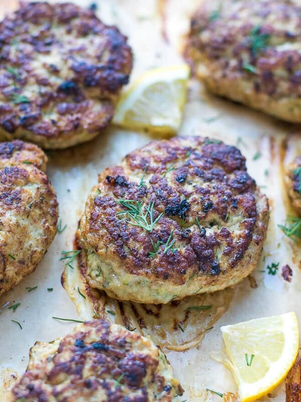 Oven Baked Turkey Zucchini Burgers Recipe. Turkey zucchini patties on parchment paper, topped with dill.