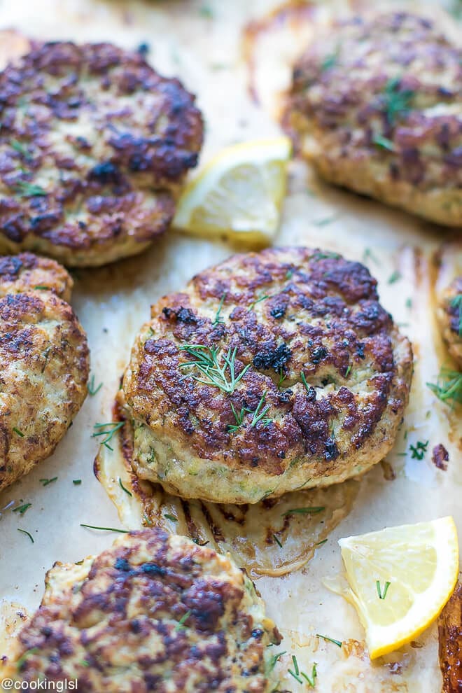Oven Baked Turkey Zucchini Burgers Recipe. Turkey zucchini patties on parchment paper, topped with dill.