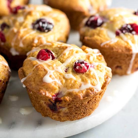 Healthy Cranberry Orange Muffins Recipe Refined Sugar Free -light and fluffy muffins with cranberries on top, drizzled with glaze.