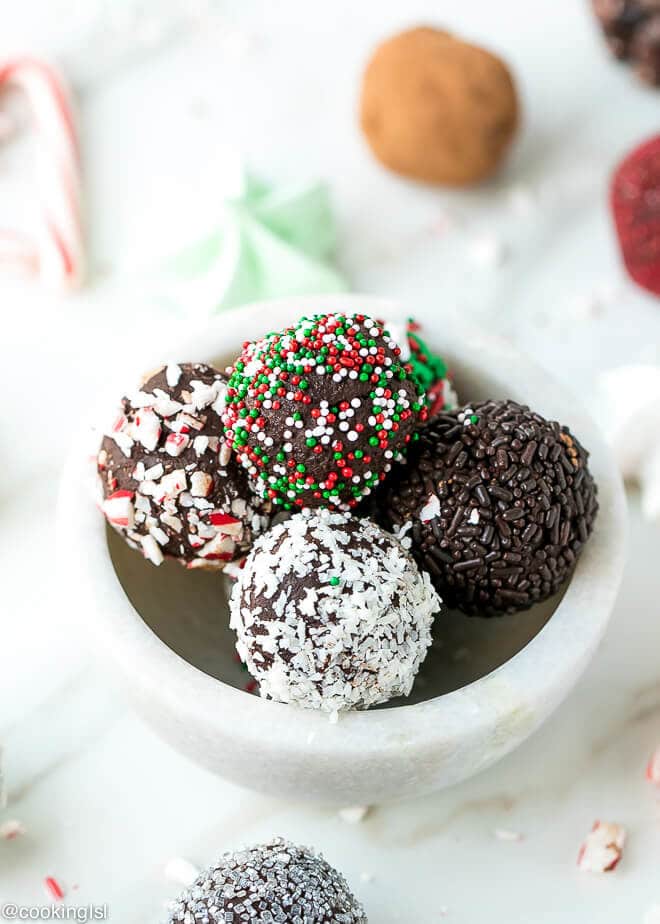 Dark chocolate peppermint truffles recipe. A bowl full with truffles, placed on a white table, with candy canes and meringue cookies on the side.