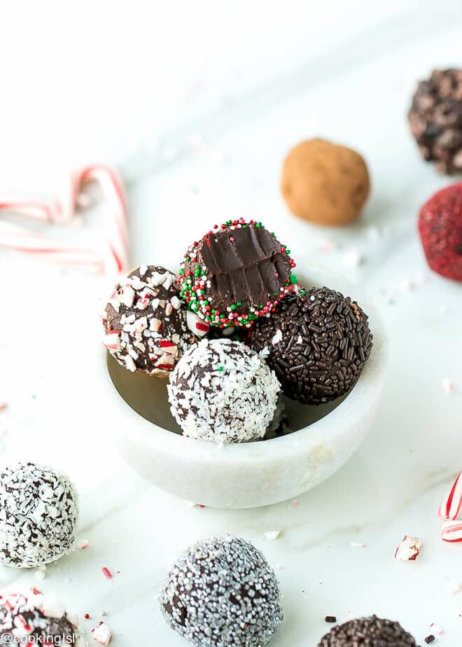 Dark chocolate peppermint truffles recipe. A bowl in a holiday setting with truffles covered in sprinkles.