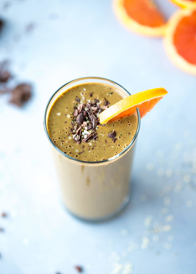chocolate orange smoothie in a clear glass topped with cacao nibs