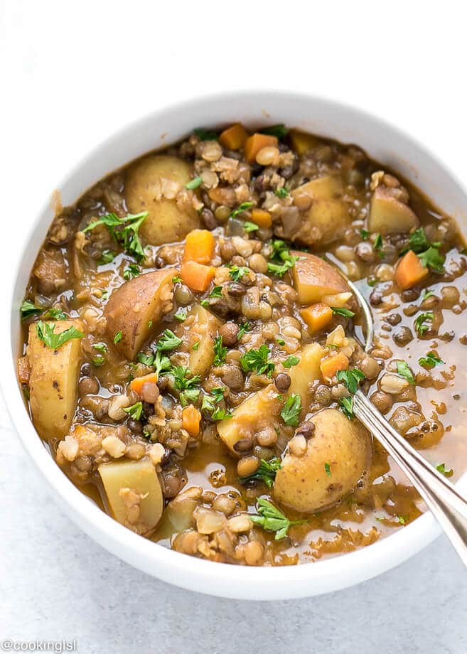 Lentil Potato Soup Recipe, Lentil Soup in a white ceramic bowl with a spoon inside, topped with parsley.