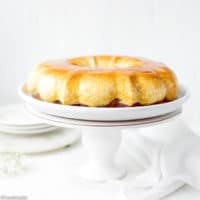 Easy Chocoflan Recipe - Kodrit Kadir. Creme caramel flan in a bundt pan, inverted over a white platter on a cake stand.