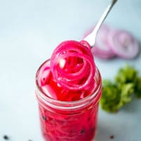 How To Make Pickled Onions - Easy Pickled Red Onions Recipe in a small clear glass jar onion rings with a rich purple color.