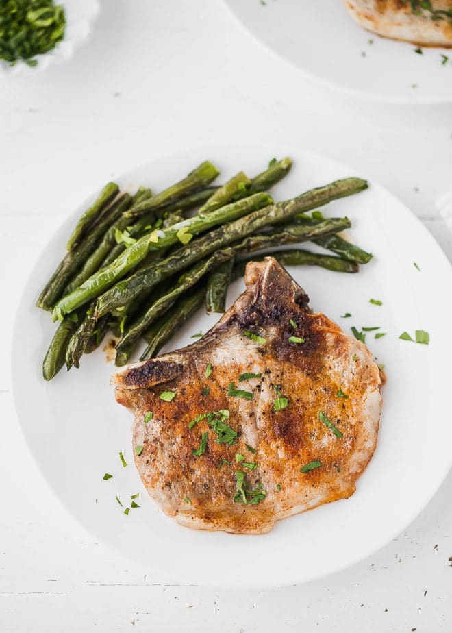 oven baked bone-in pork chops on a white plate