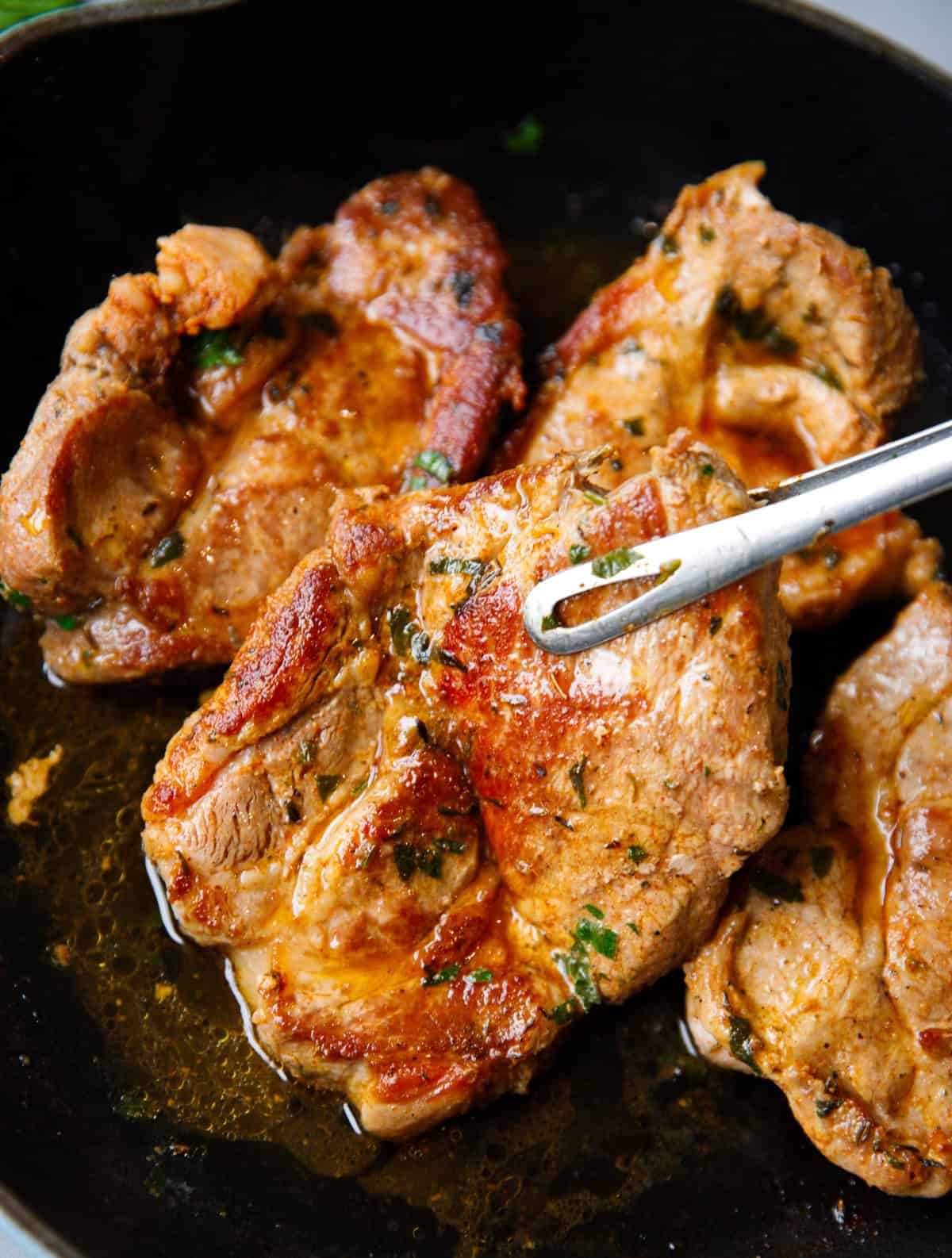 Golden brown pork shoulder steaks cooked in cast iron skillet