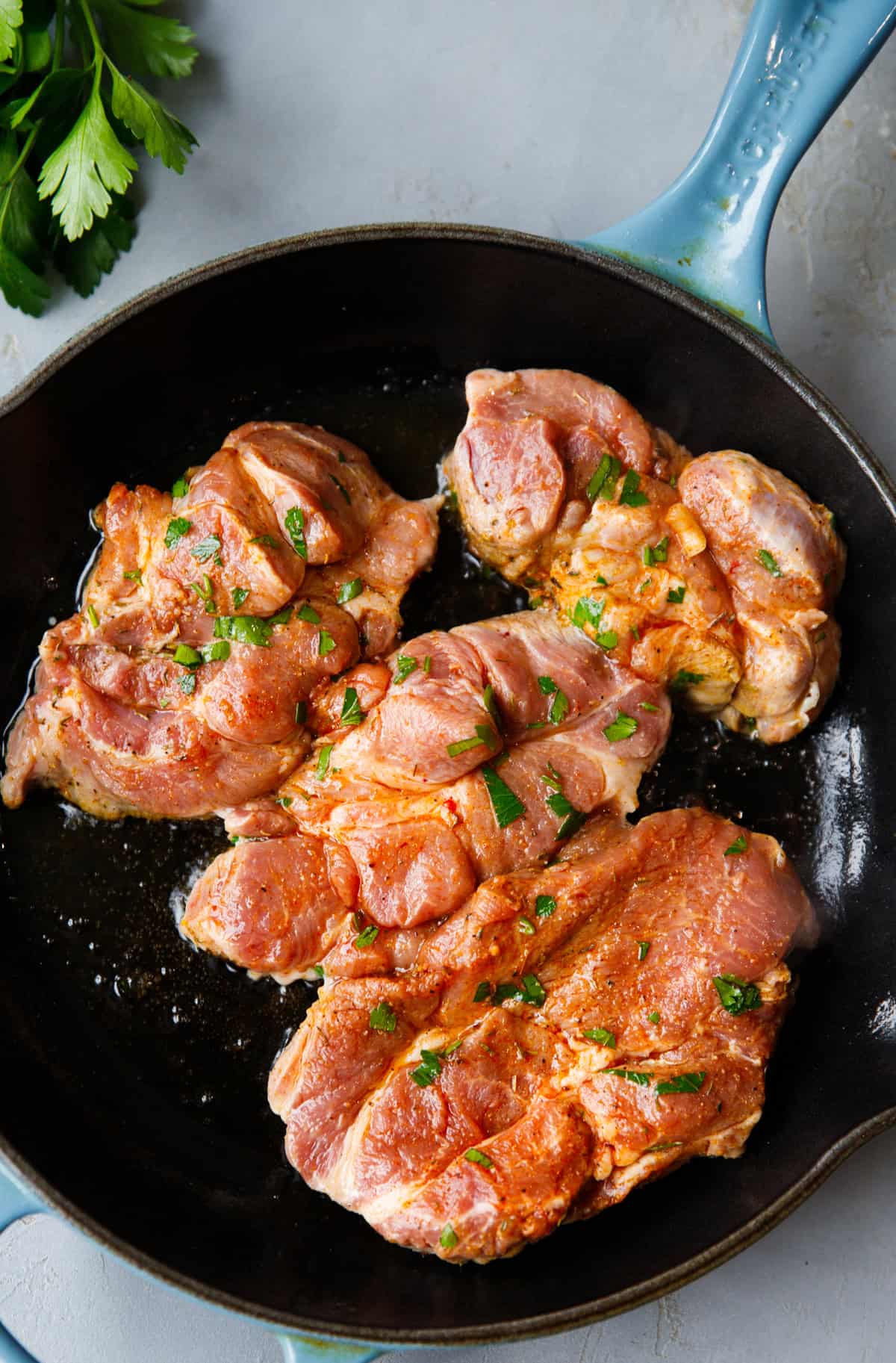 Marinated pork shoulder steaks cooking in cast iron skillet