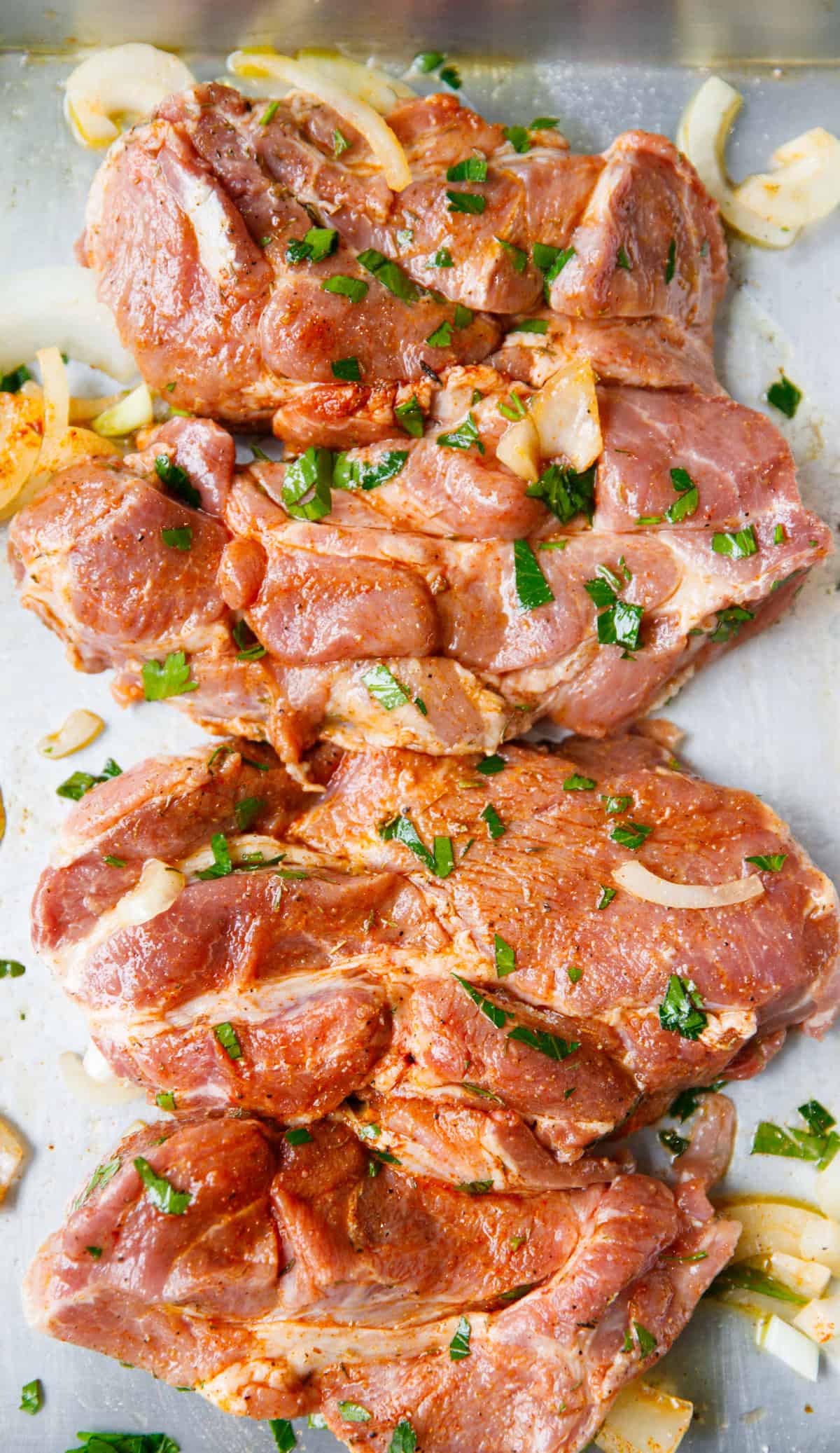 Marinated pork shoulder steaks with herbs and spices on tray