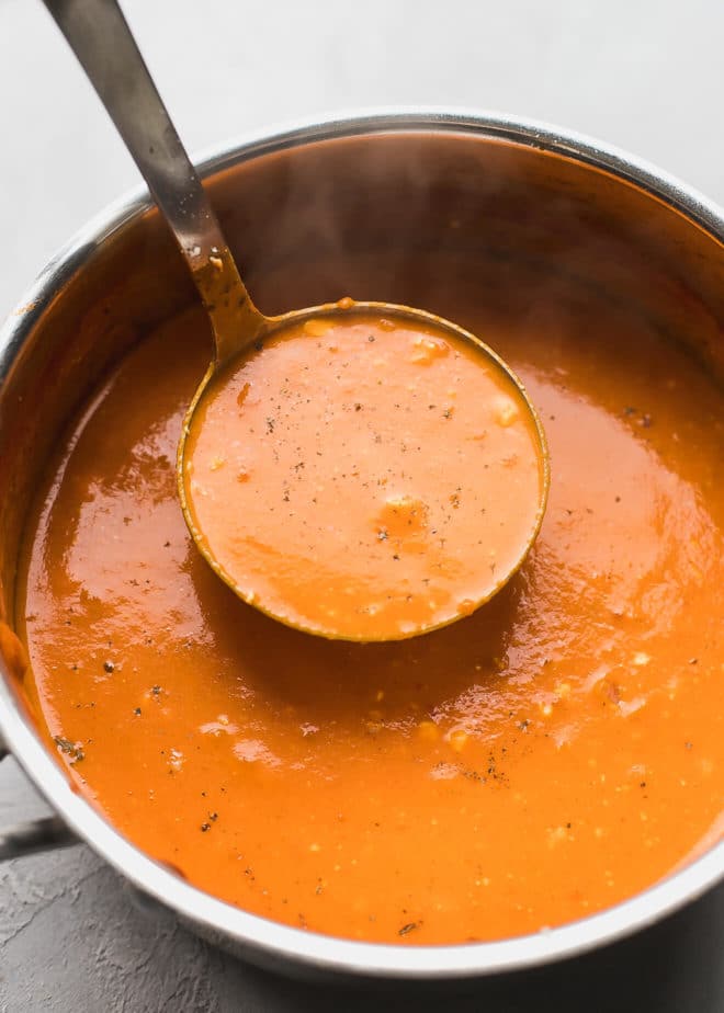 Tomato feta soup in a pot with a ladle