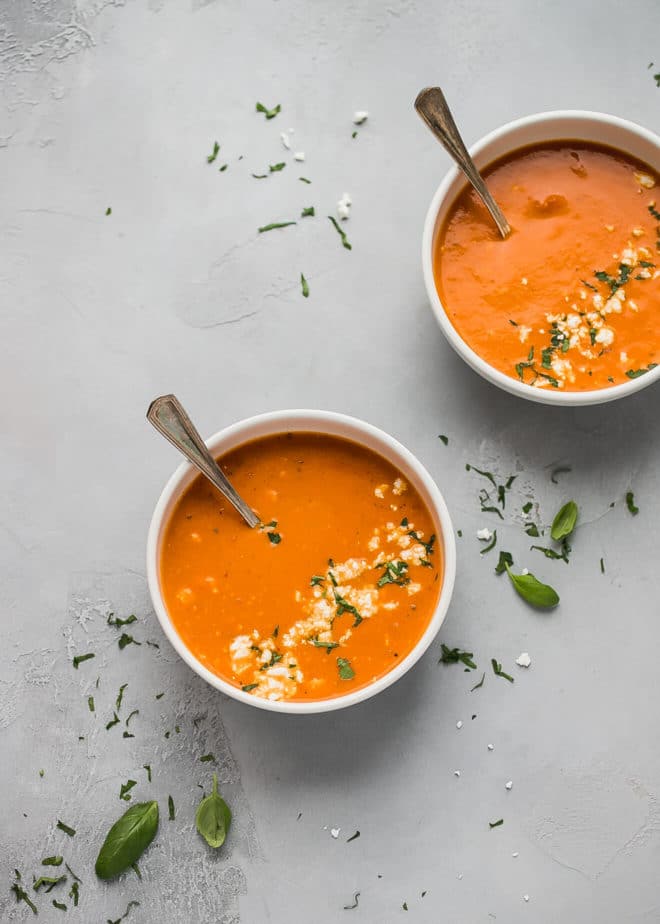 Orange colored tomato feta soup in white bowls