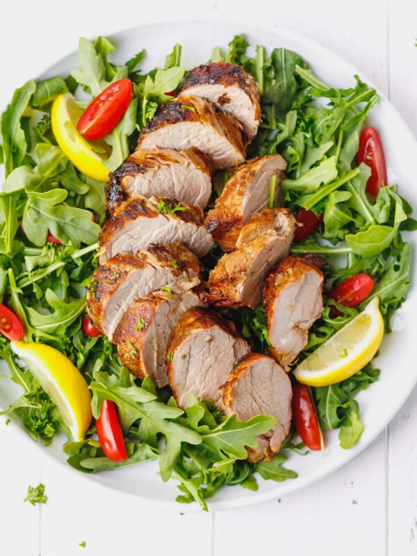 Grilled pork tenderloin, sliced on a platter with salad