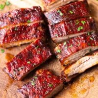 Juicy oven-baked St. Louis style ribs sliced on a wooden board and brushed with glossy barbecue sauce.