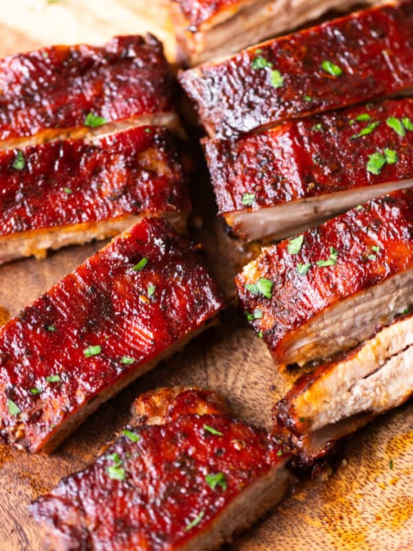 Juicy oven-baked St. Louis style ribs sliced on a wooden board and brushed with glossy barbecue sauce.