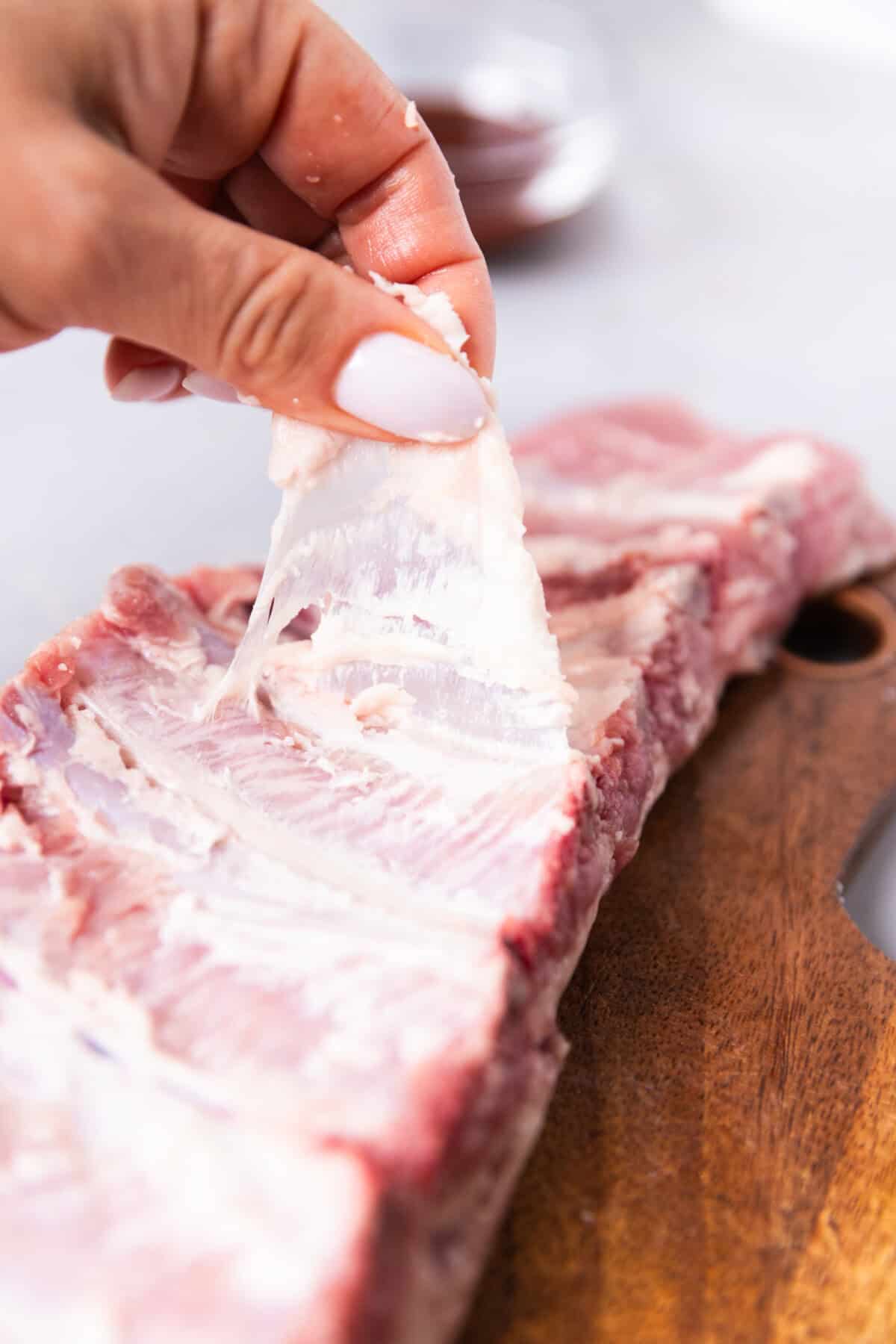 Removing the thin membrane from the back of a rack of St. Louis style ribs before seasoning.