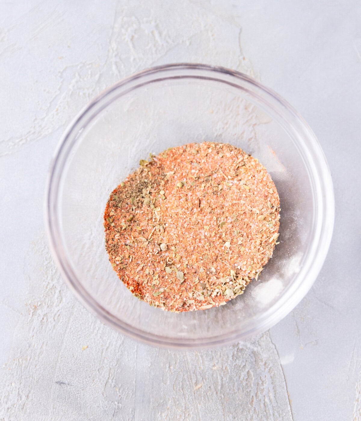 Bowl with mixed paprika, brown sugar, garlic powder, oregano, cayenne, and salt for homemade rib rub.