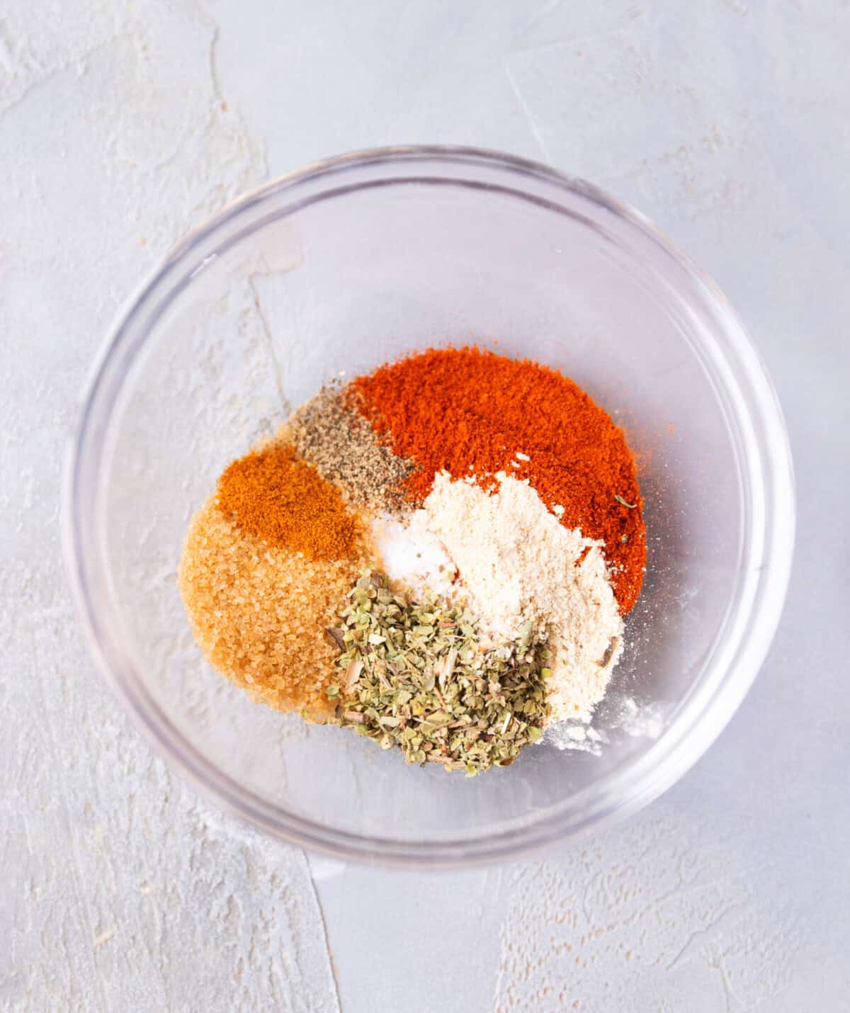 Bowl with paprika, brown sugar, garlic powder, oregano, cayenne, and salt for homemade rib rub.