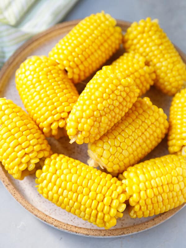 Close-up of boiled corn on the cob sprinkled with salt and pepper, showing juicy yellow kernels.