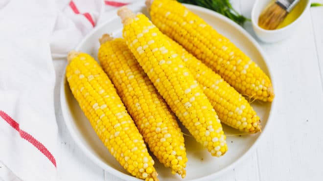 Ears or boiled corn on the cob on a white plate
