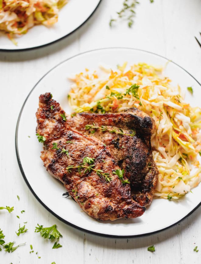 How To Cook Pork Shoulder Steak. Charred pork shoulder steaks on a plate with salad