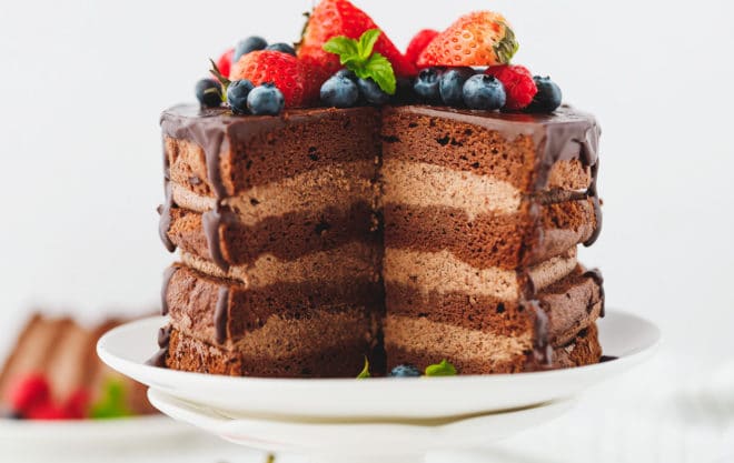Keto chocolate cake on a cake stand with slices cut out
