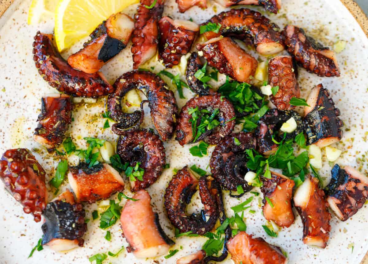 Charred grilled octopus on a speckled plate