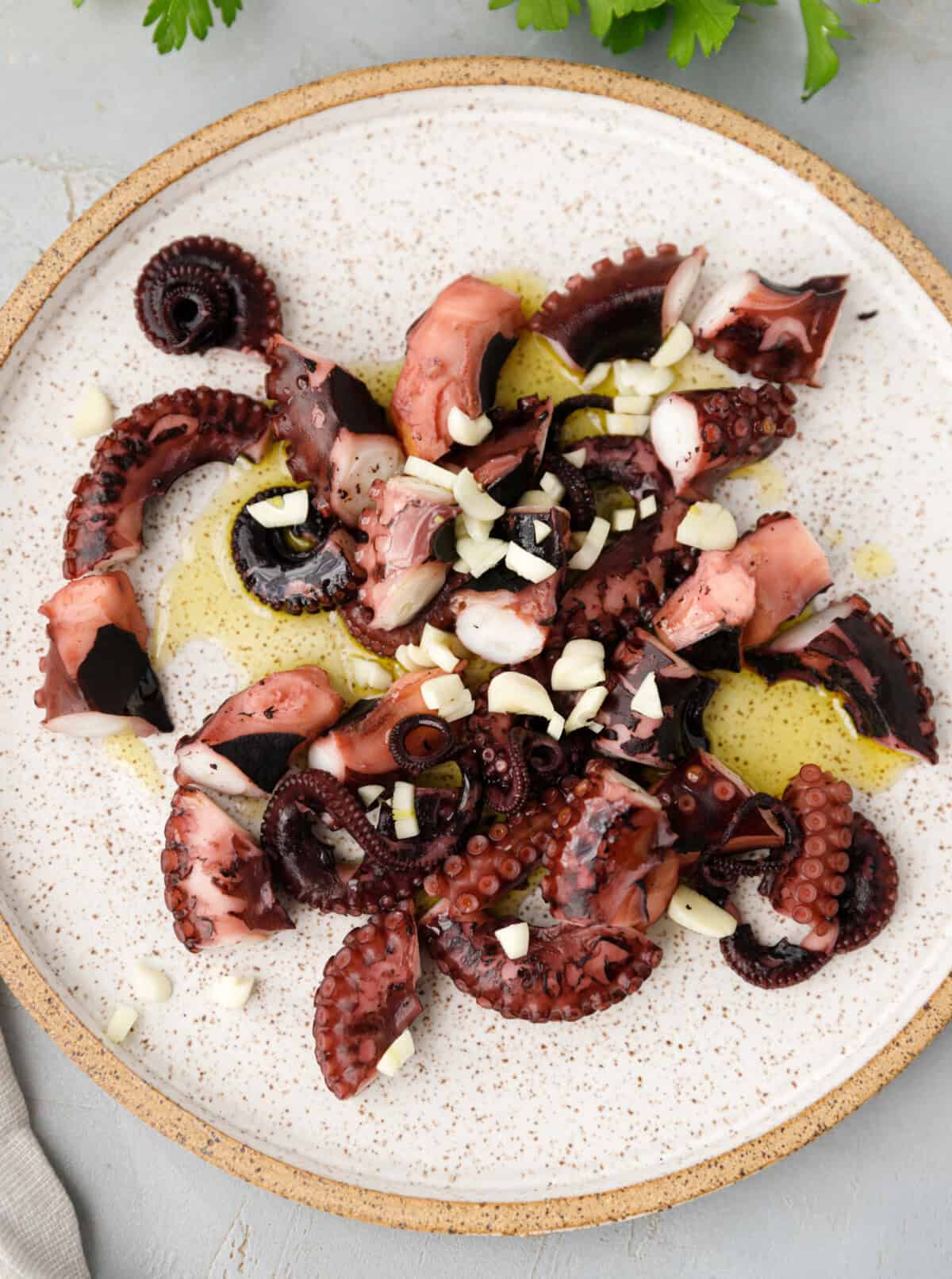 Marinated octopus with garlic and olive oil on plate.