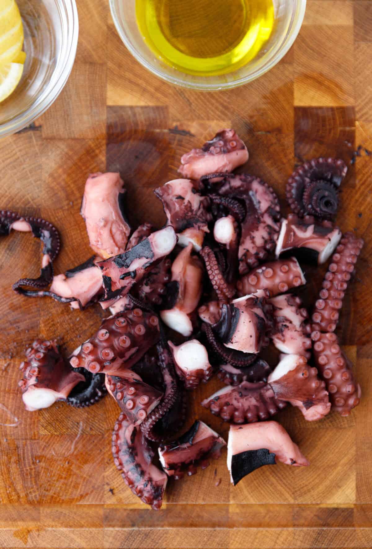 Chopped octopus pieces ready for grilling on cutting board.