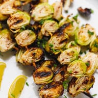 Charred grilled brussel sprouts on a skewer on a plate