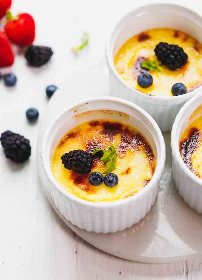Low-carb creme brulee in white ramekins topped with berries