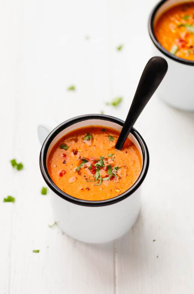 Roasted red pepper soup in a mug with a spoon