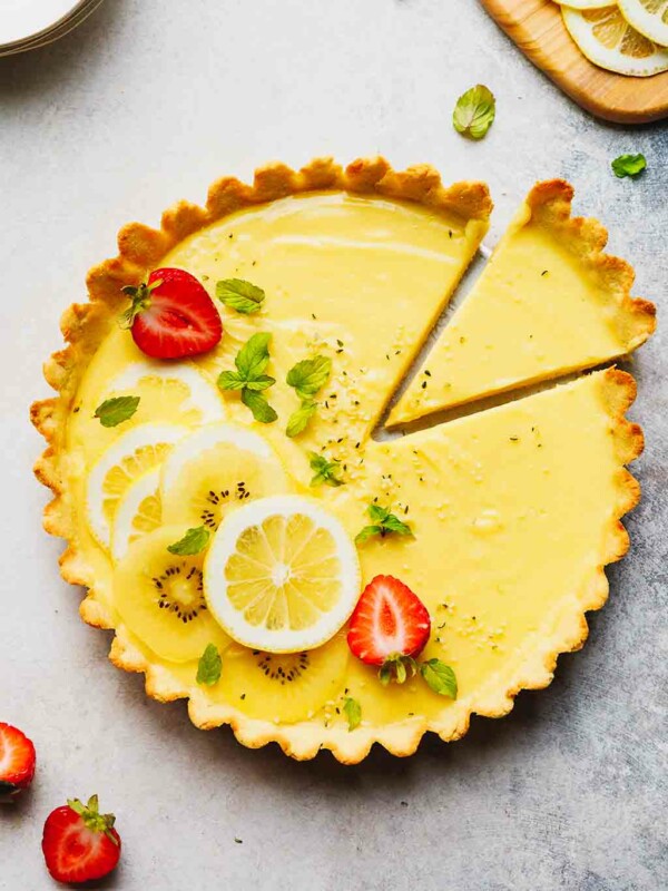 Low-carb lemon tart on a table, topped with strawberries and lemon slices