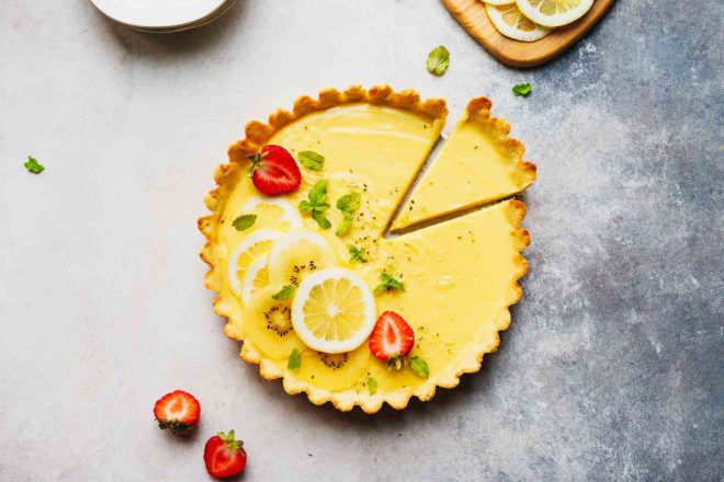 Low-carb lemon tart on a table, topped with strawberries and lemon slices