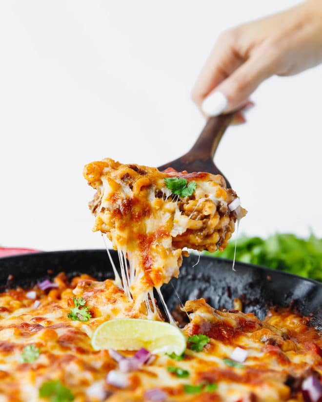 Cheesy chili mac & cheese casserole in a skillet with a serving spoon