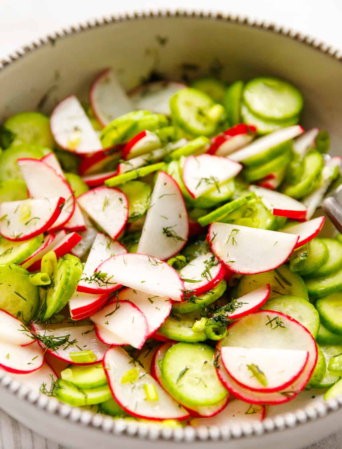 close up cucumber radish salad with dill and sliced cucumbers and radishes