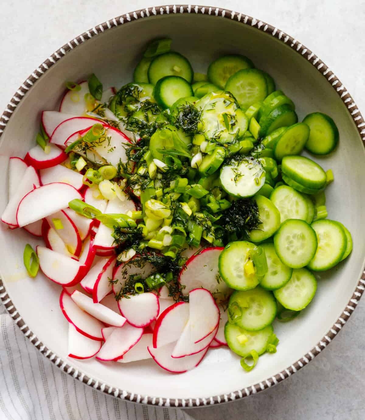 cucumber radish salad ingredients with sliced cucumbers radishes dill and green onions in bowl