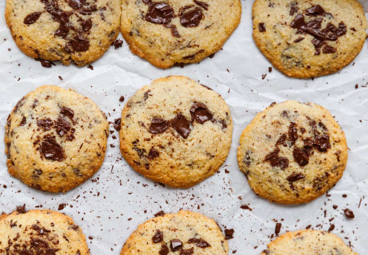 Keto chocolate chip cookies on parchment paper with melted dark chocolate chunks and golden edges