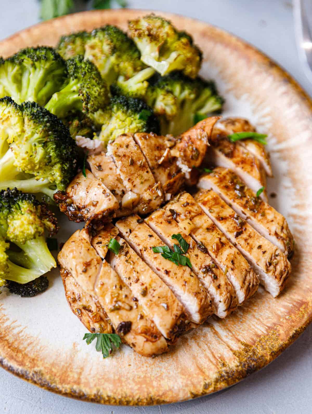 Plate of juicy balsamic baked chicken breast with roasted broccoli, garnished with fresh parsley for a healthy, easy weeknight dinner.