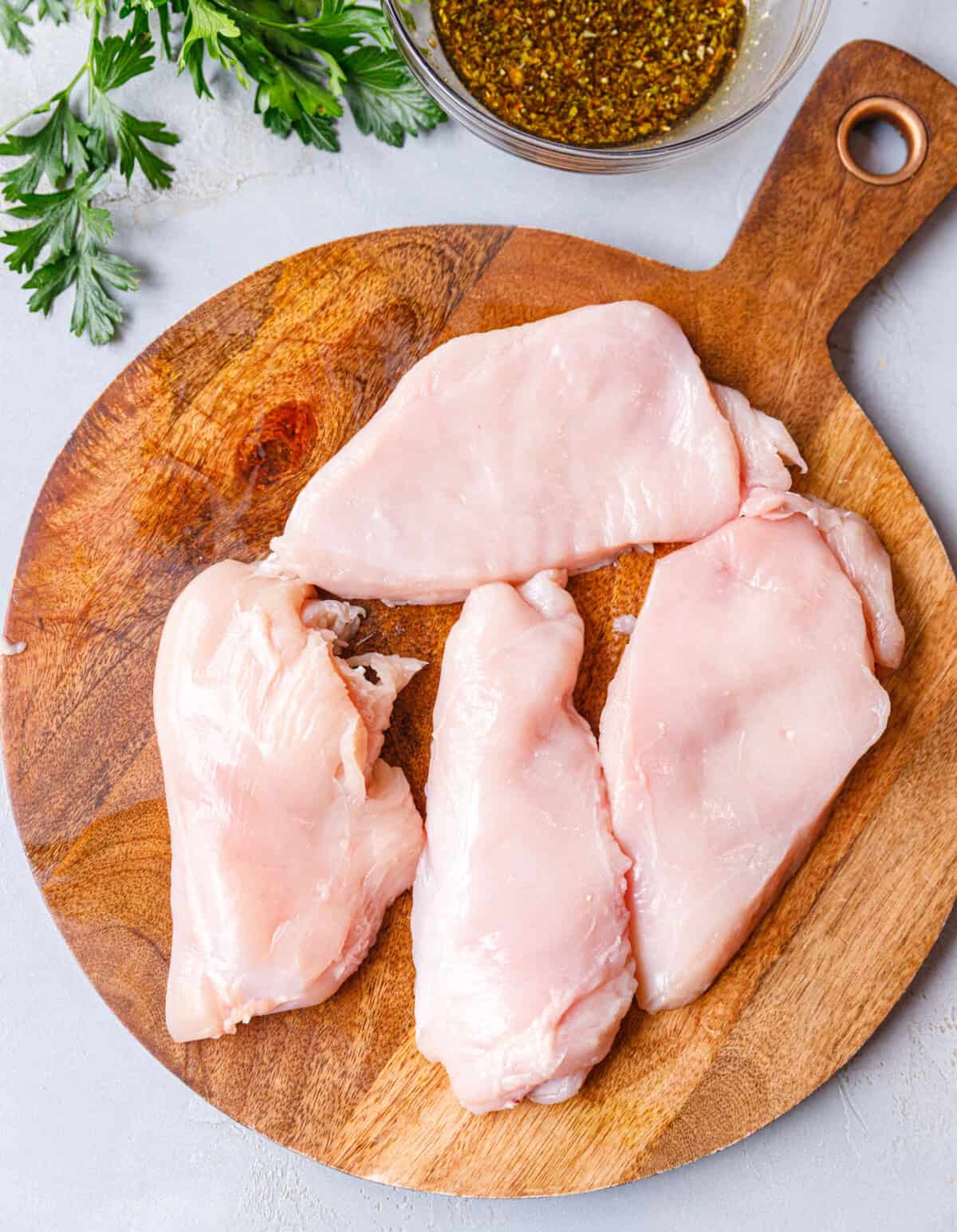 Flattened chicken breasts on wooden board