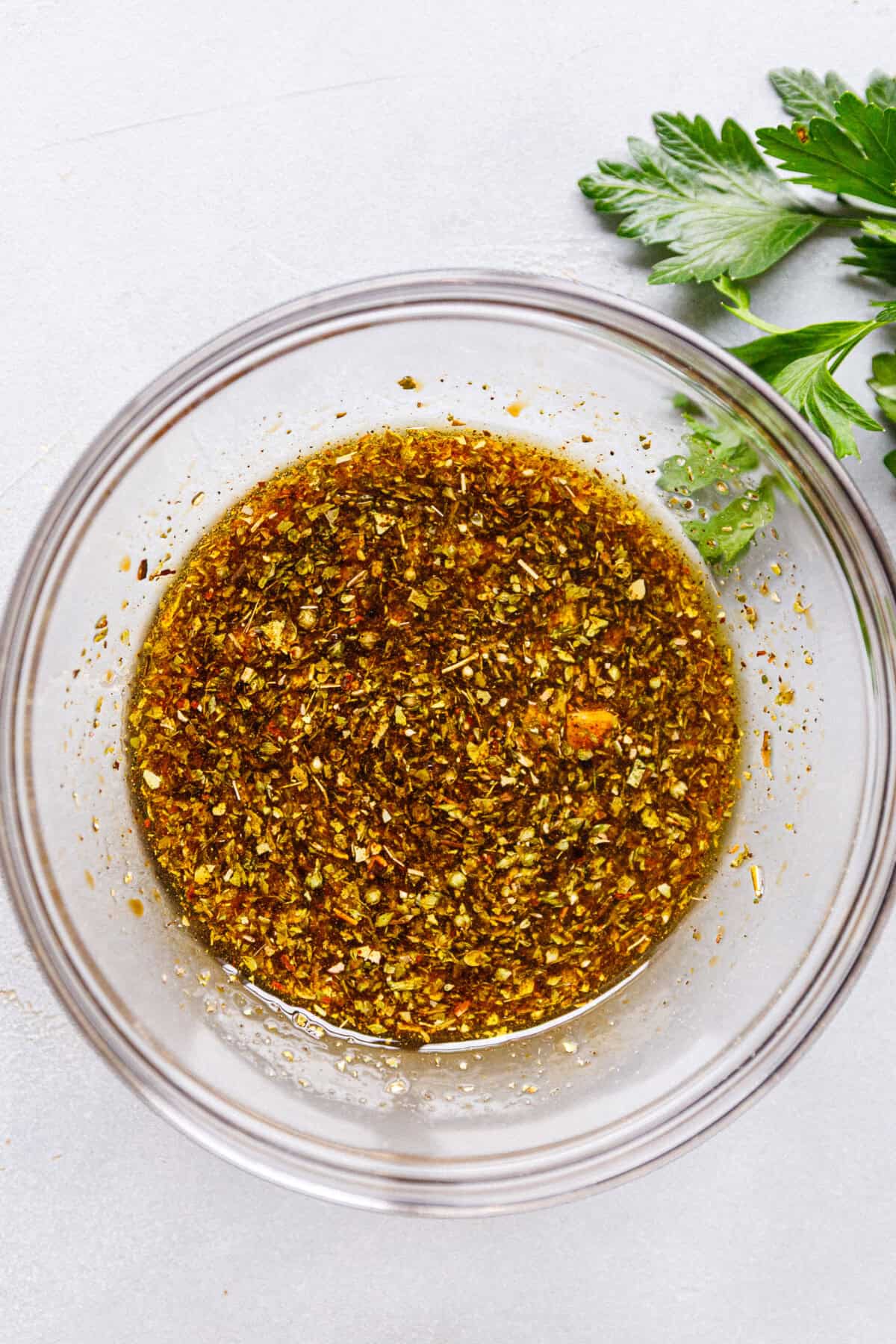 ``A glass bowl with Balsamic, soy sauce, olive oil, garlic, salt, pepper and oregano marinade for chicken.