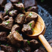 Keto steak bites in a skillet with wooden spoon