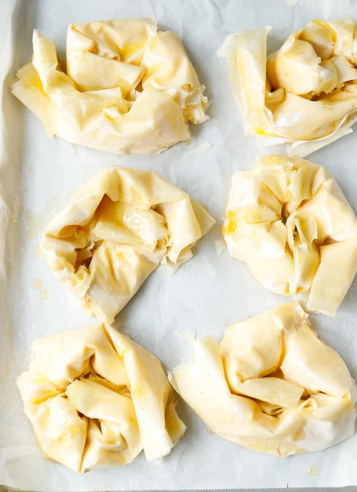 Unbaked Bulgarian banitsa swirls made with phyllo dough and feta cheese on a parchment lined baking sheet