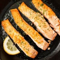 Pan seared salmon fillets with fresh dill and lemon in cast iron skillet