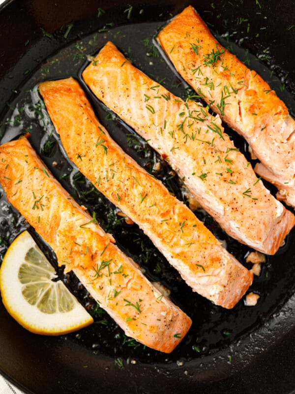 Pan seared salmon fillets with fresh dill and lemon in cast iron skillet