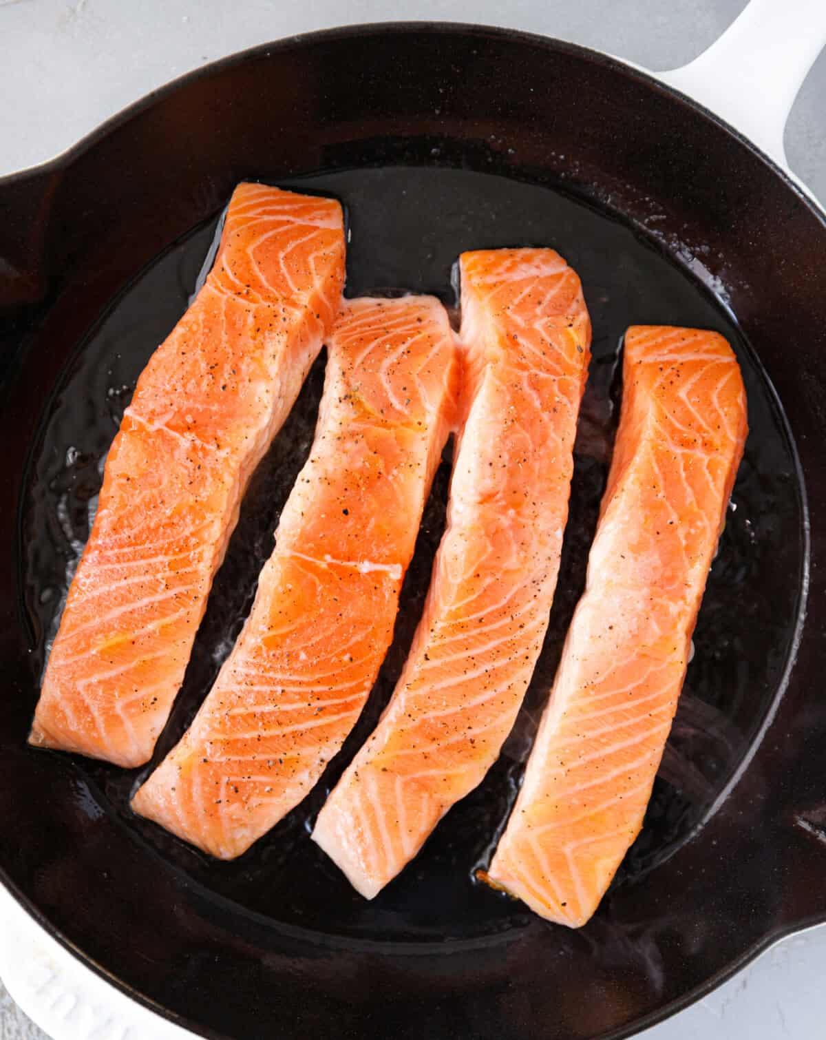 Salmon fillets cooking in a cast iron skillet for pan seared salmon recipe